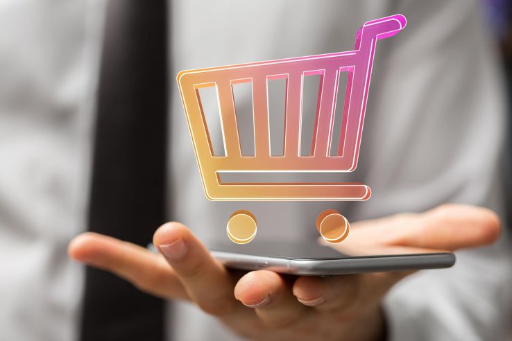 Smartphone in der Hand und darüber ein Warenkorb-Icon