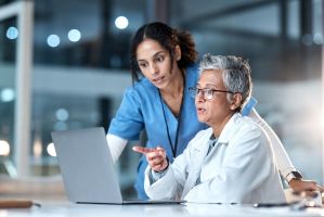 Zwei Frauen beraten sich und schauen auf den gleichen Bildschirm vor sich.