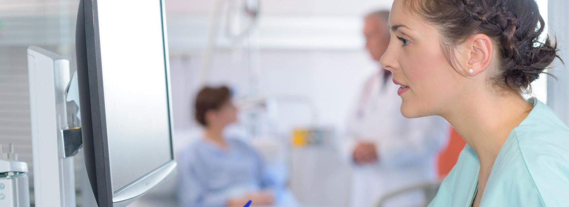 Eine Pflegerin sitzt am Computer und macht Notizen auf einem Block