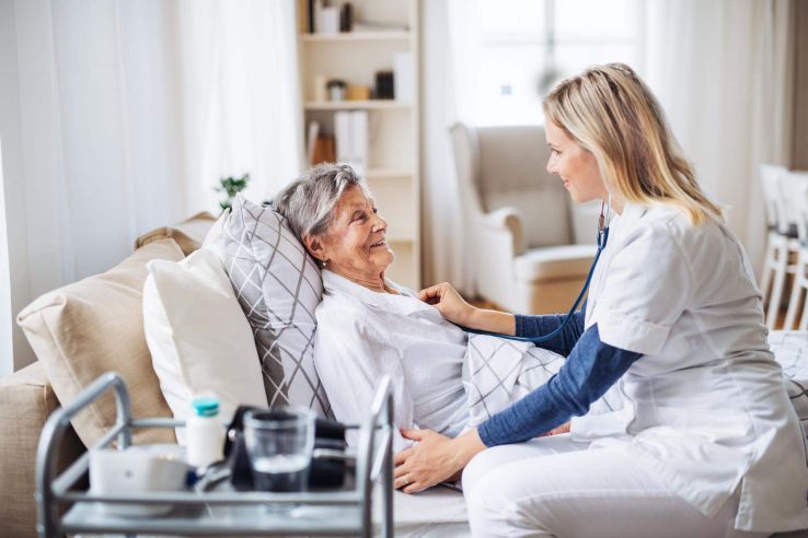 Eine Ärztin sitzt bei einer Patientin am Bett und untersucht sie